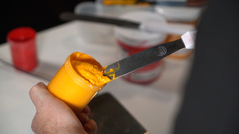 wadah dengan tinta kuning dicampur dengan spatula tinta