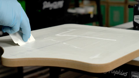 Tangan bersarung menyeka perekat berbasis air di sekitar papan dengan kartu pembersih