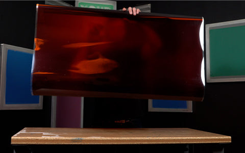 Seorang pria memegang film merah di atas meja di kamar gelap